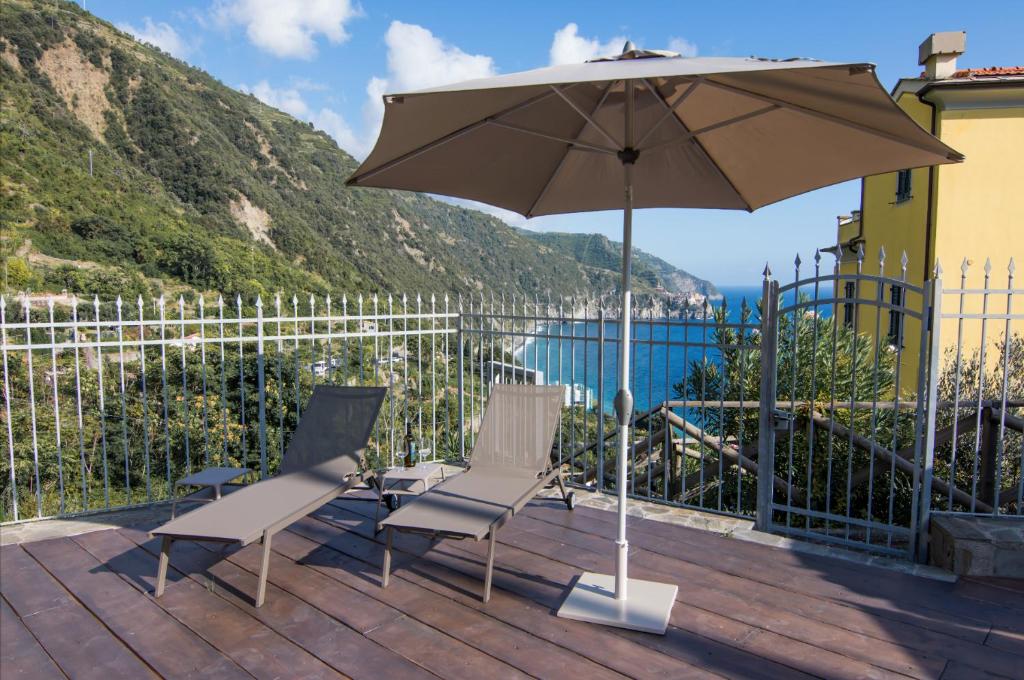Parte do hotel com chão de madeira, duas cadeiras e um guarda-sol marrom ao ar livre com vista para as montanhas e mar azul, ilustrando post Hotéis em Cinque Terre.