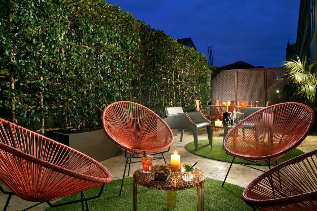 Lounge compartilhado do Milan Suite Hotel com alguns vasos de plantas, cadeiras, meinhas e iluminação indireta