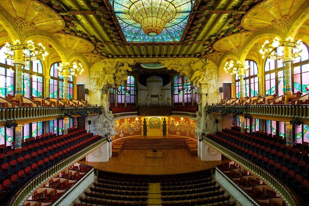 Interior do Palácio de Música Catalã. A sala de concertos tem cadeiras dos dois lados em três andares O lugar é repleto de vitrais coloridos, mosaicos e esculturas, e uma grande claraboia está no teto. - Foto: Jiuguang Wang via Wikimedia Commons