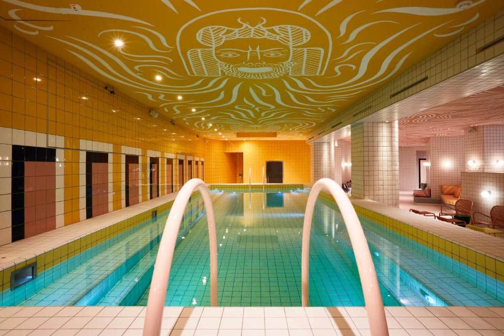 piscina coberta no Mama Shelter Roma, uma das opções de onde ficar em Roma, com escadinha e afrescos no teto em dourado, formando uma carinha brava