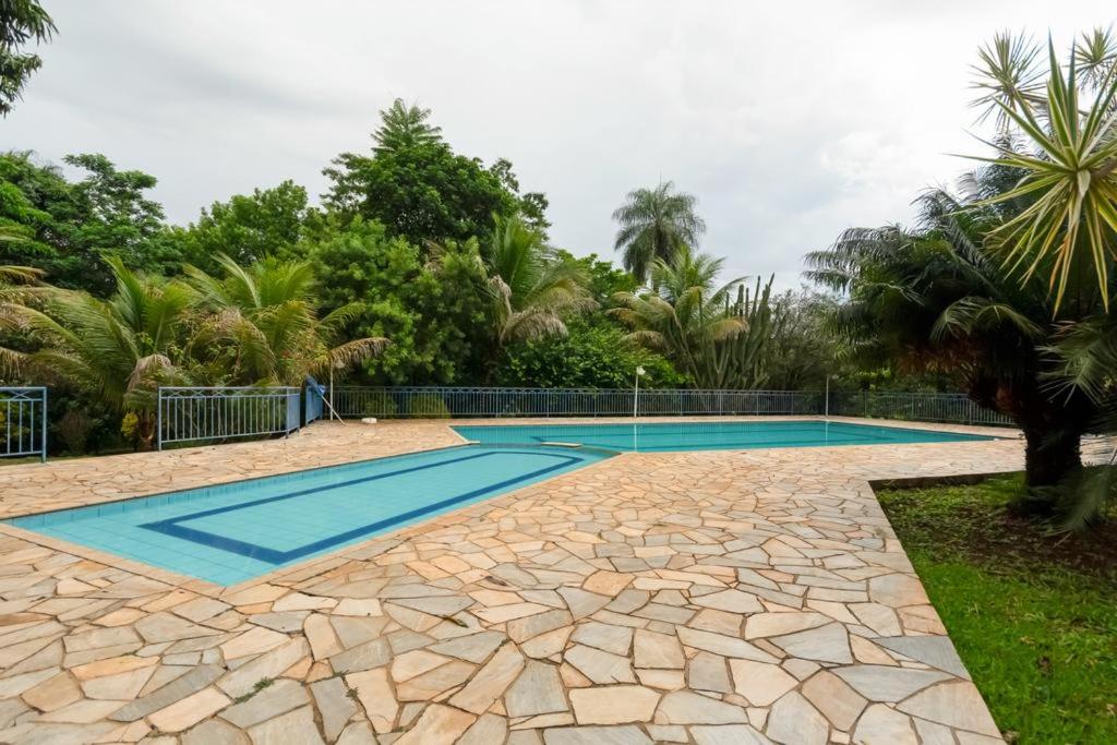 Área da piscina do Jardin Park Hotel, em Jardinópolis. A piscina é larga e comprida e há muito verde em volta.