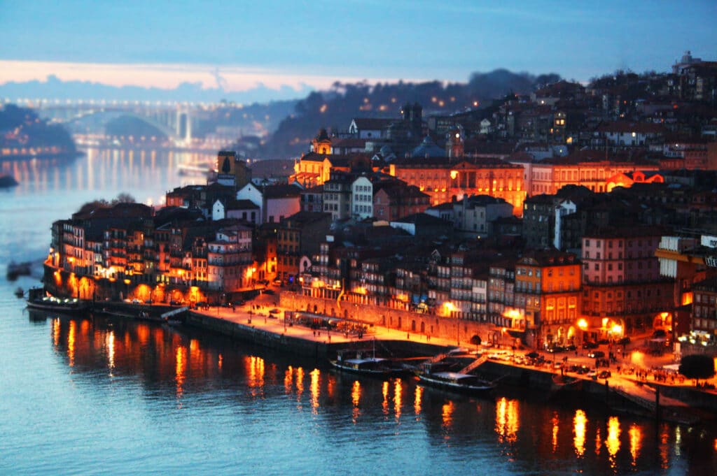 Imagem no final do dia em Porto em Portugal com rio a frente e ao fundo várias casas.