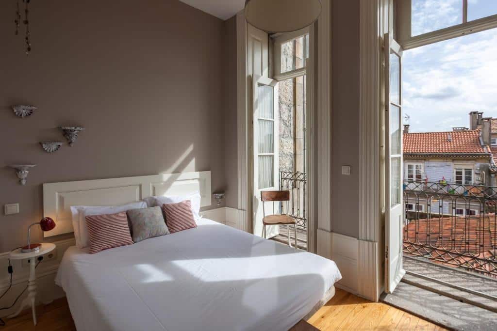 Quarto privado Being Porto Hostel com cama de casal do lado esquerdo da foto do lado direito duas portas que dá acesso a varanda.
