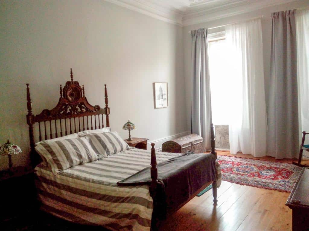 Quarto da Casa Familiar do Porto com cama de casal do lado esquerdo e duas cômodas ao lado com luminária. Representa airbnb no Porto.