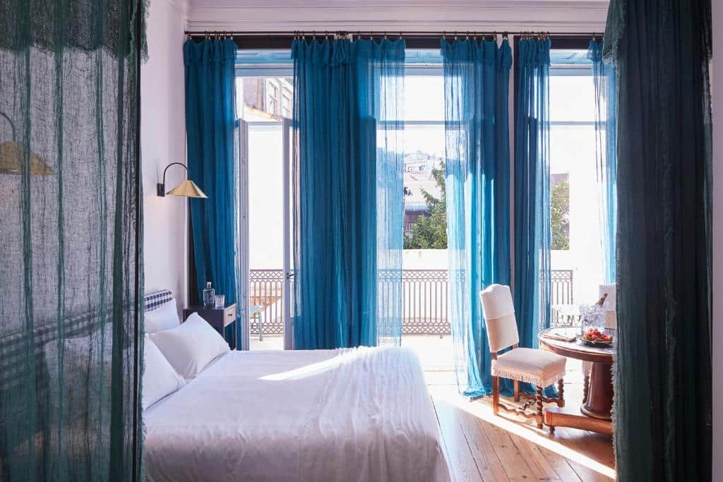 Quarto do Cocorico Luxury House – Porto com cama de casal do lado esquerdo da imagem e em frente a cama uma mesa com cadeira. Representa hotéis boutique no Porto.