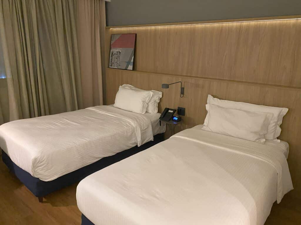 Quarto com duas camas de solteiro e uma mesinha de cabeceira ao centro no Hampton inn By Hilton