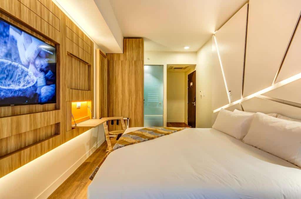 Quarto do Hotel Nodo – Primer hotel explorador urbano com cama de casal do lado direito, em frente a cama uma TV presa na parede. Representa hotéis em Providencia em Santiago.