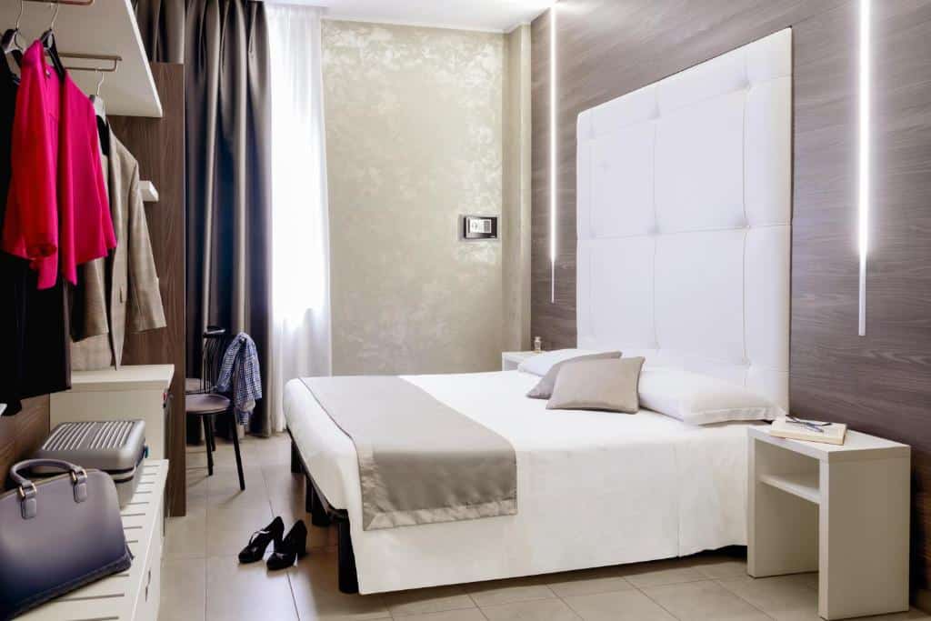 Quarto do Ibis Styles Milano Centro com uma janela, uma cama de casal com uma cabeceira estofada, um armário de conceito aberto e uma mesa de escritório com uma cadeira