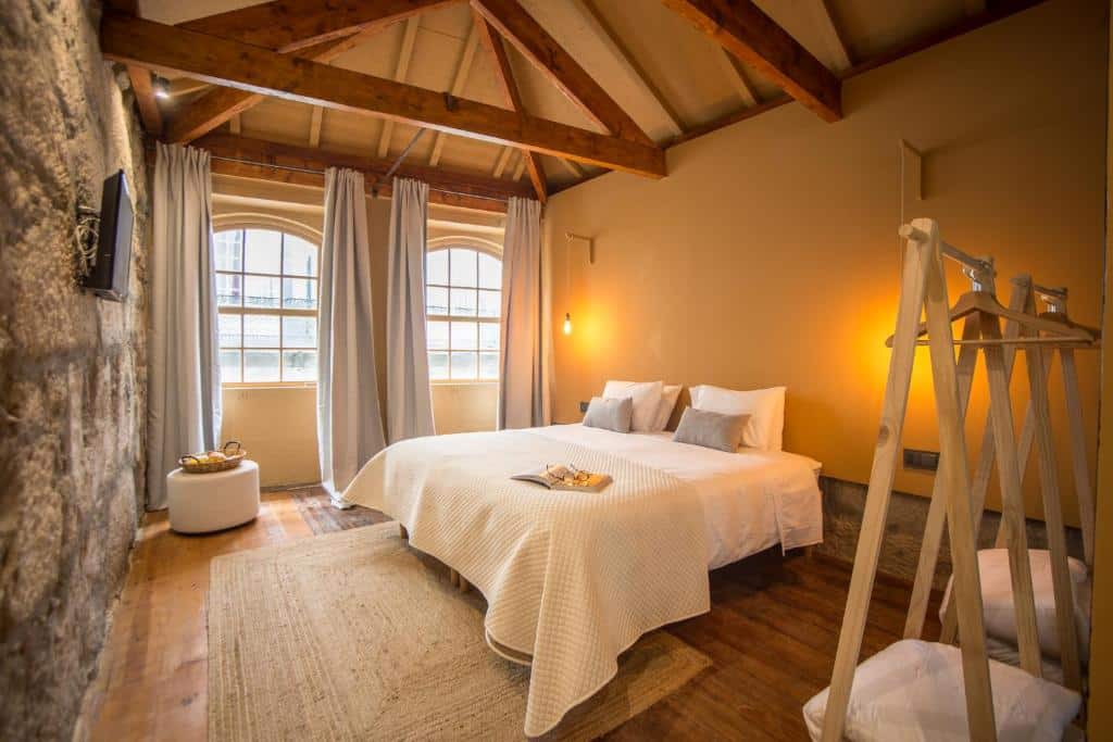 Quarto do Laurear Guest House com cama de casal do lado direito e em frente a cama uma TV pendurada na parede. Representa hotéis românticos no Porto.