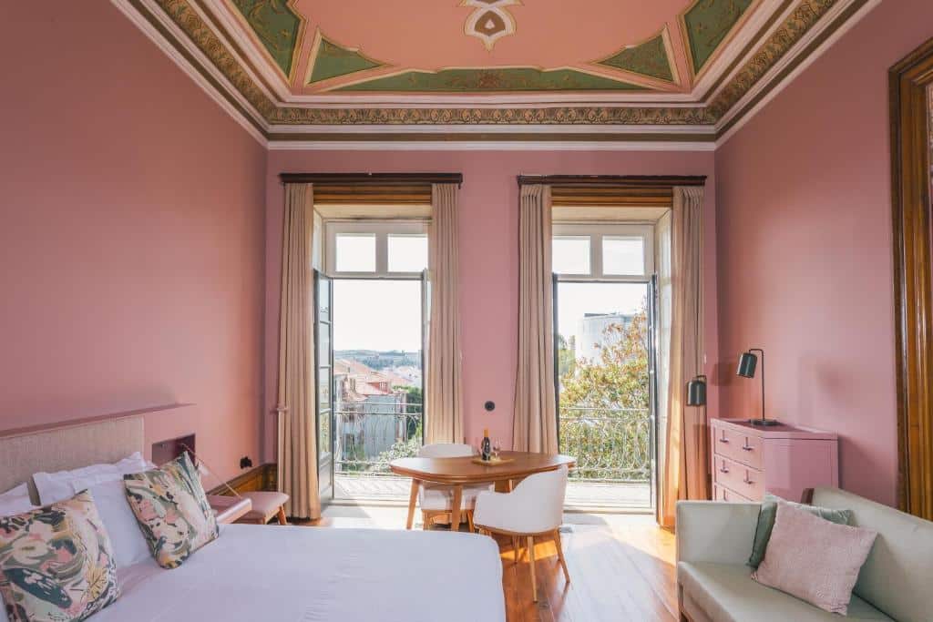 Quarto do Menina Colina Guesthouse com cama do lado esquerdo da imagem e em frente a cama um sofá. Representa hotéis no centro do Porto.