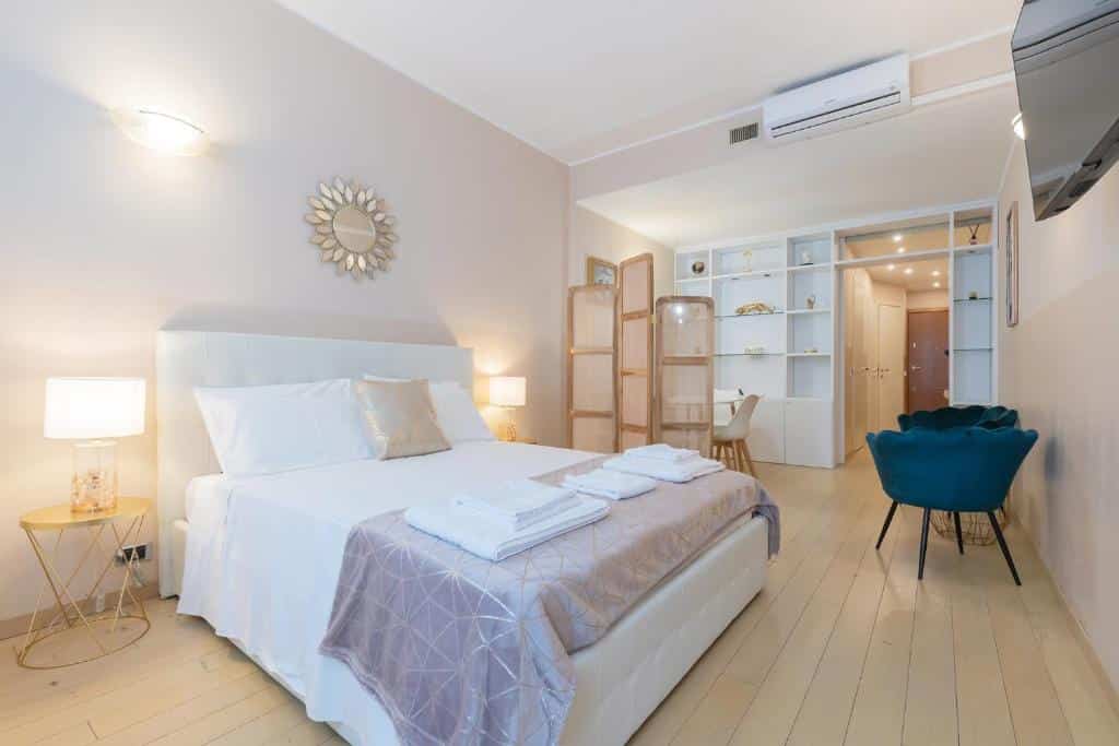 Quarto do Milan Retreats Duomo com uma cama de casal, uma televisão, uma mesinha redonda com duas poltronas, há também duas mesinhas de cabeceira com abajures, para representar airbnb em Milão