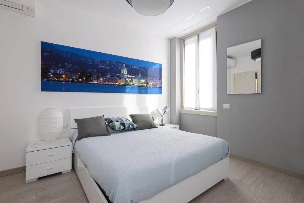 Quarto do Milan Center Apartment Studio - Porta Romana com uma cama de casal, uma janela, um quadro sob a cama, duas mesinhas de cabeceira om abajur e um espelho