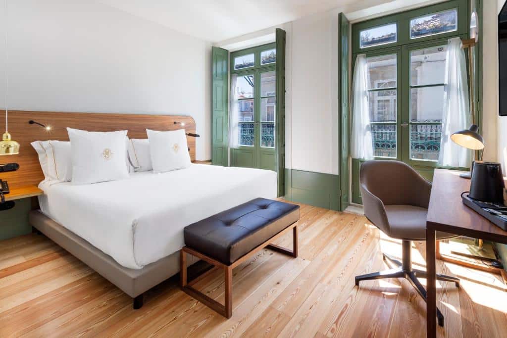Quarto do One Shot Aliados Goldsmith 12 com cama de casal do lado esquerdo da imagem a frente a cama mesa de trabalho de madeira e cadeira. Representa hotéis baratos no Porto.