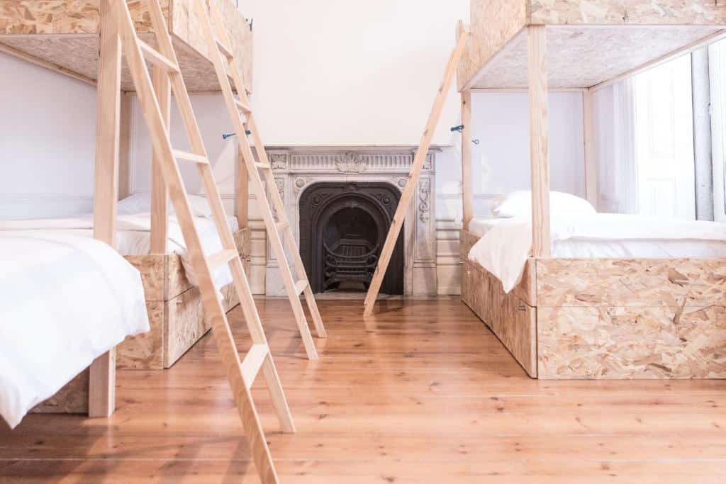 Quarto compartilhado do Porto Republica Hostel & Suites com duas camas de beliche de cada lado e no meio uma lareira. Representa hostels no Porto.