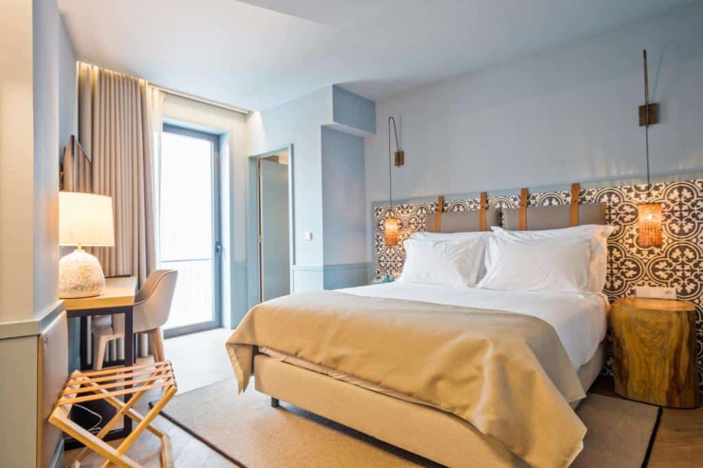 Quarto do Pur Oporto Boutique Hotel by actahotels com cama de casal do lado direito, do lado esquerdo da cama uma mesa de trabalho com cadeira. Representa hotéis no centro do Porto.
