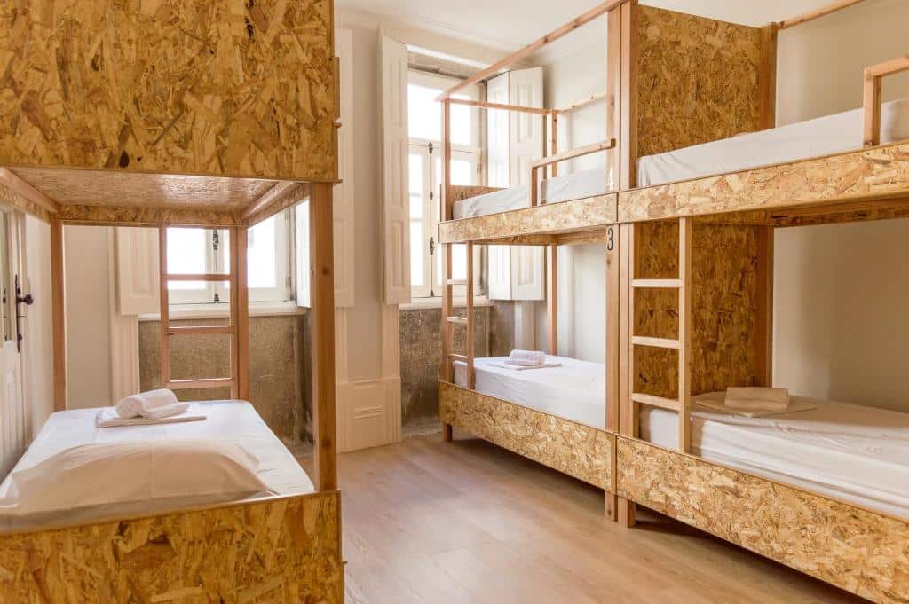 Quarto do Queen’s Garden Hostel  com três camas de beliche de madeira.