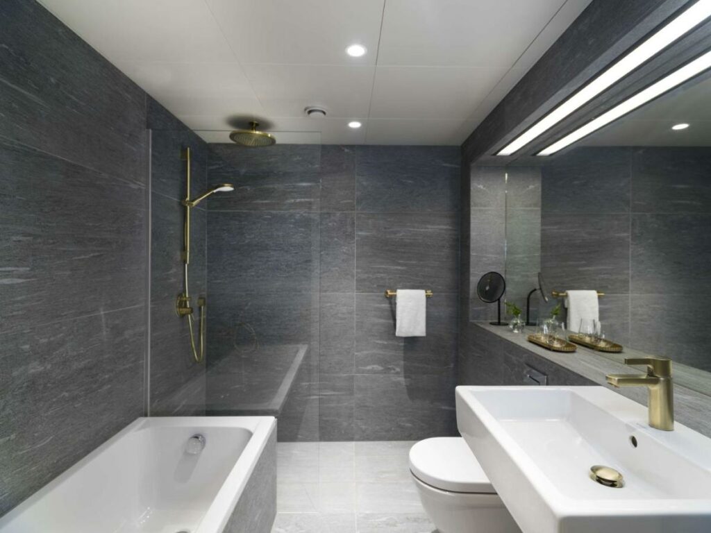Banheiro do Radisson Collection Royal Hotel com uma banheira, chuveiro, pia, vaso sanitário e espelho.