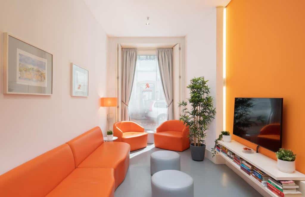Sala de estar do Porto Lounge Hostel & Guesthouse com sofá do lado esquerdo e em frente ao sofá um rack e uma TV presa na parede.