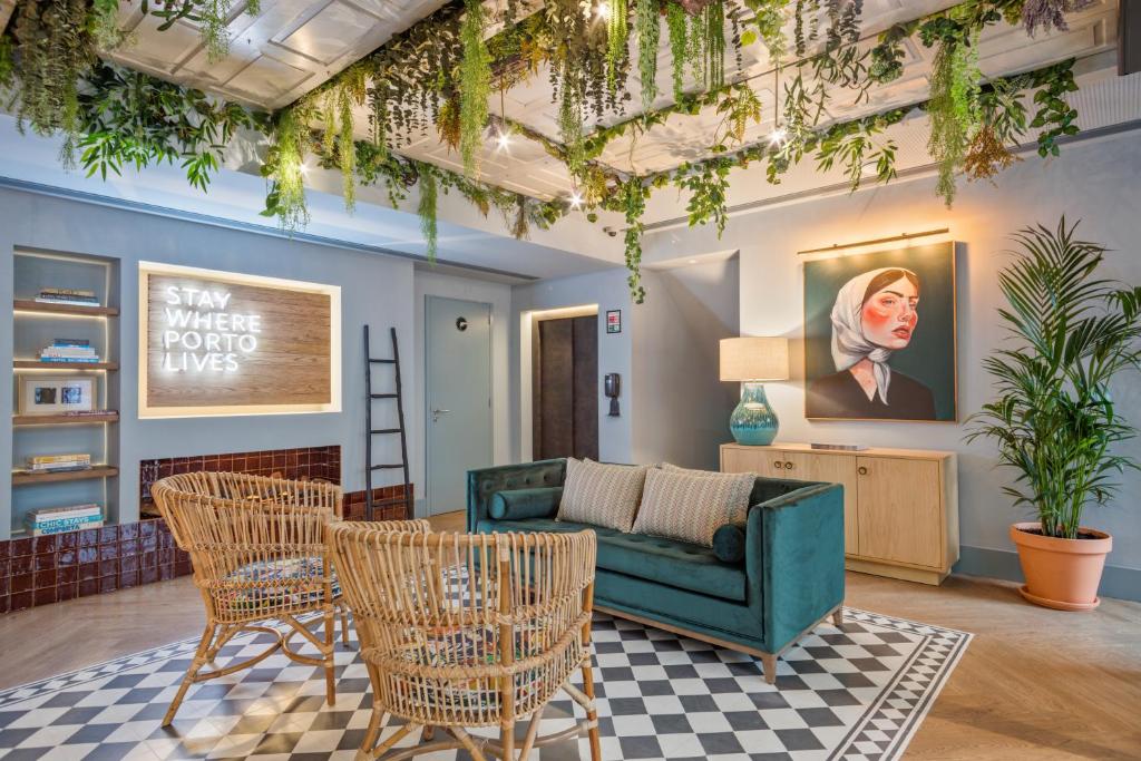 Sala de estar do Pur Oporto Boutique Hotel by actahotels com duas cadeiras de madeira a frente e ao fundo um sofá de cor verde de dois lugares.