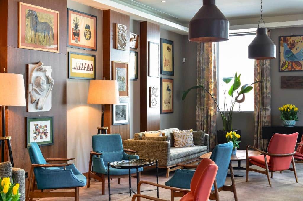 Sala de estar do The Editory Artist Baixa Porto Hotel com sofás e poltronas no ambiente e paredes cheias de quadro.