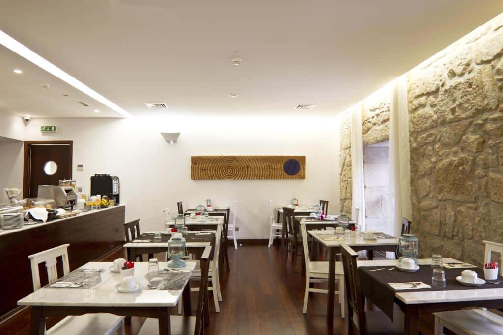 Sala de refeição do Ribeira do Porto Hotel com várias mesas e cadeiras.