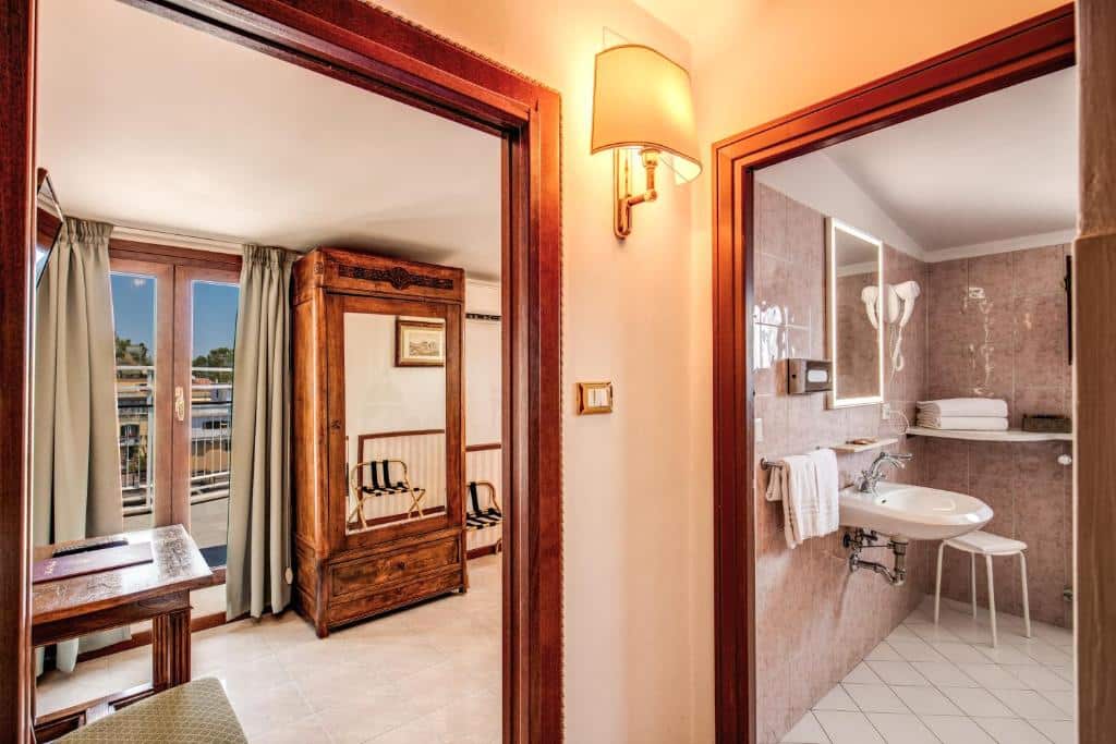 sala de estar do Hotel Pacific com móveis de madeira com espelho e vista do banheiro que parece ter adaptações para PcDs