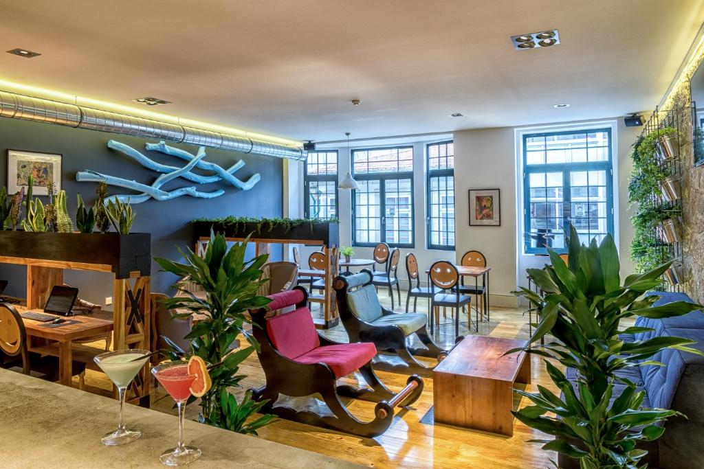 Sala de estar do Nice Way Porto com cadeiras, sofás e plantas no ambiente.