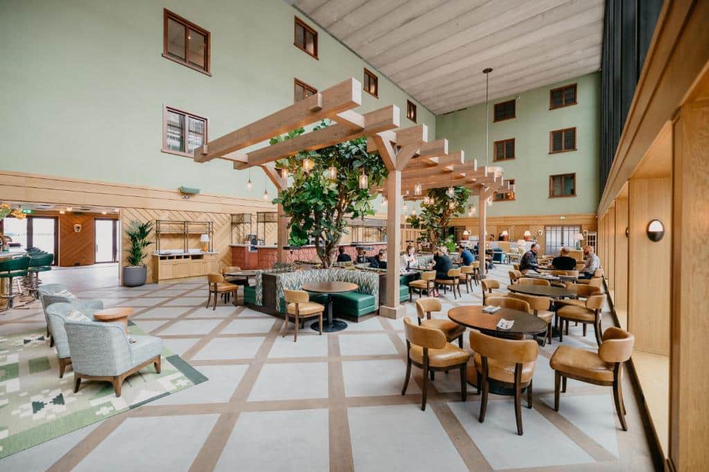 Área com mesas, cadeiras e poltronas do Hotel BOAT & CO. A área é espasosa e com uma decoração nas cores verde claro e bege claro