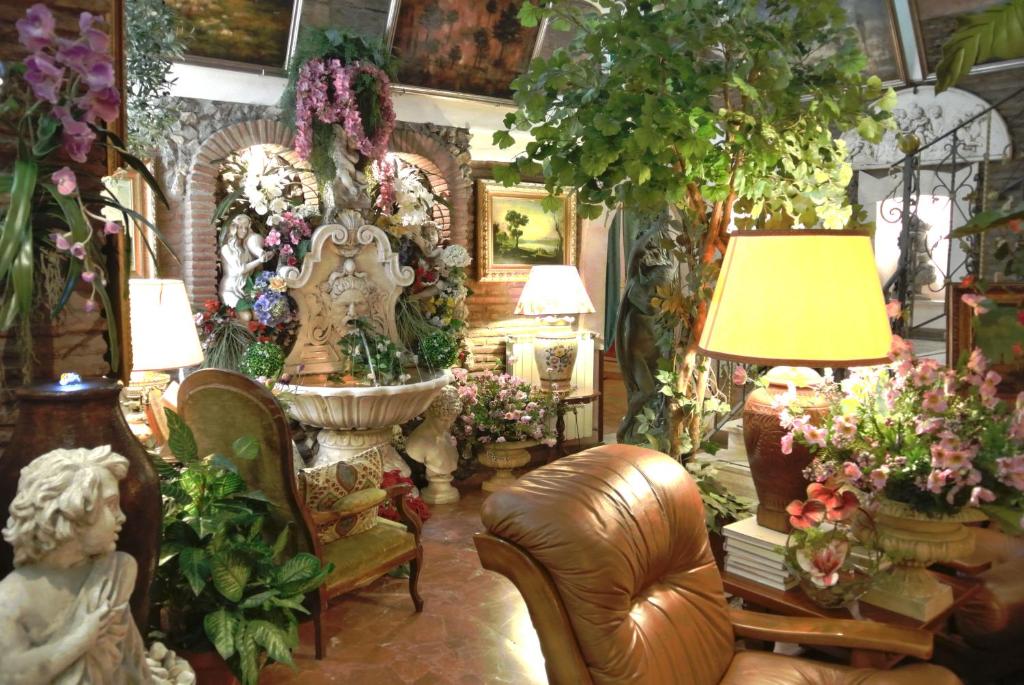 salão do Hotel Barrett com poltronas ed couro marrons, muitas plantas no chão e penduradas e várias esculturas ao estilo clássico de anjos e mini fontes