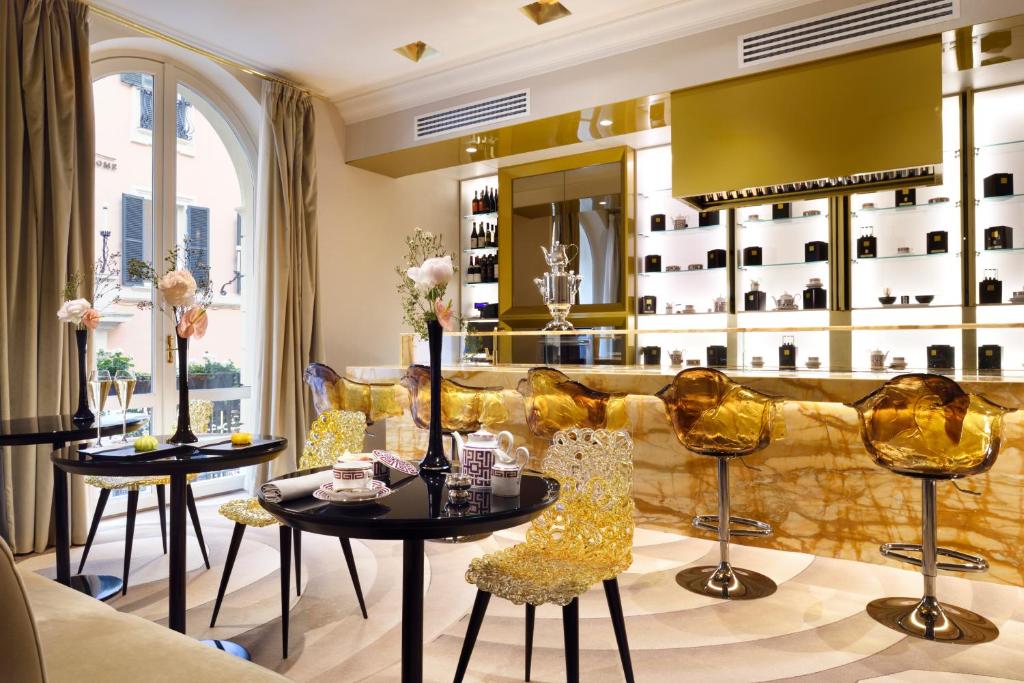 salão do The First Dolce - Preferred Hotels & Resort, com mesas redondas e poltronas, além de balcão com cadeiras altas em tons de amarelo com bebidas expostas