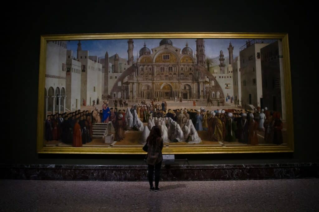Uma moça parada diante de um quadro muito amplo, que ocupa quase uma parede inteira, na Pinacoteca de Brera em Milão