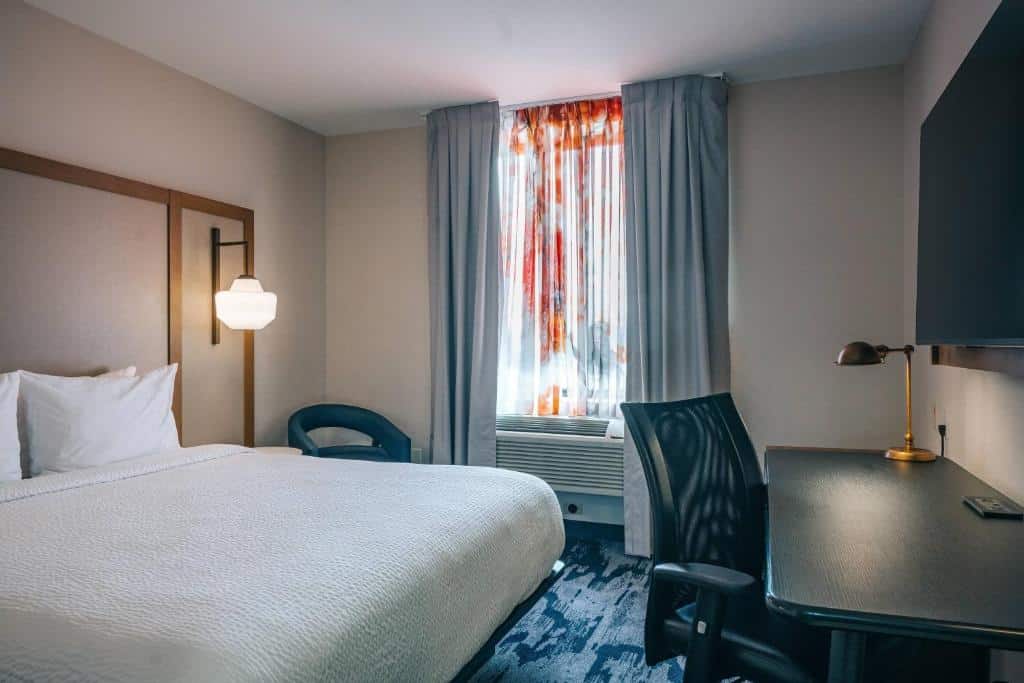 quarto do Fairfield Inn Astoria, um dos hotéis perto do aeroporto laguardia em nova york, com uma cama de casal à esquerda e uma mesa preta para trabalho à direita, em frente a cama