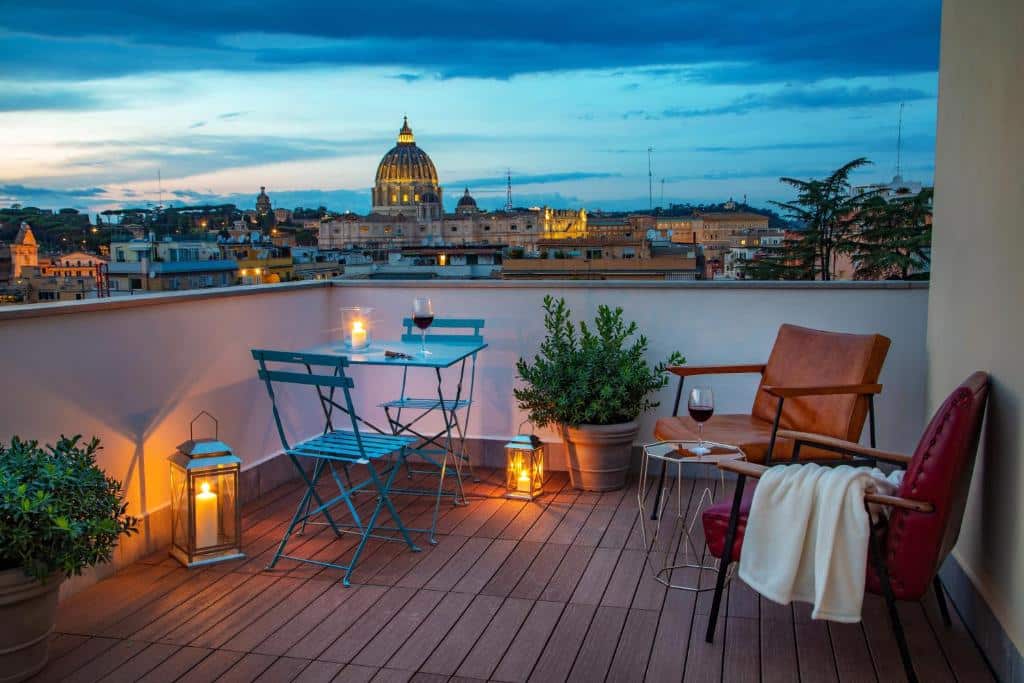 terraço do Bloom Hotel Rome com mesinha e cadeiras de madeira, além de duas poltronas com plantinhas e vista para a cidade