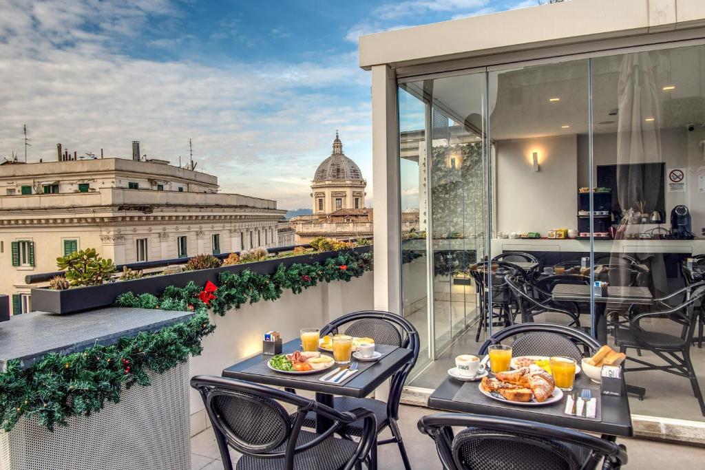 terraço do Doria Palace Boutique Hotel com mesas e cadeiras pretas com café da manhã postos, há uma área coberta e outra aberta com vista para a cidade