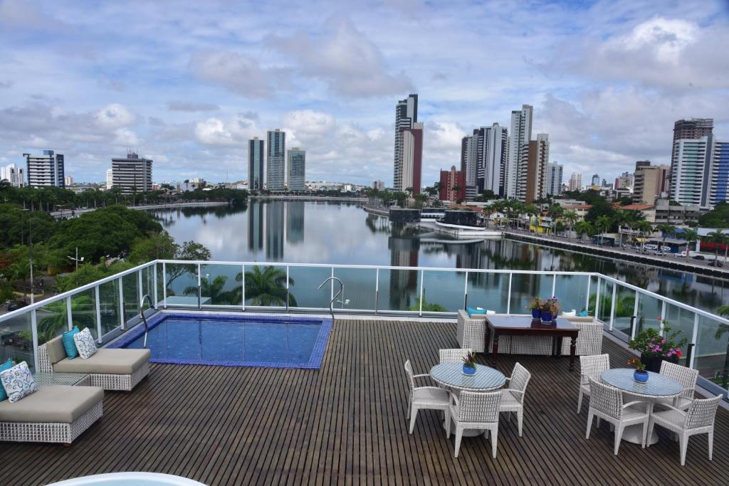Terraço de hotel com piscina, mesas, cadeiras e vista ampla para a cidade de Campina Grande.