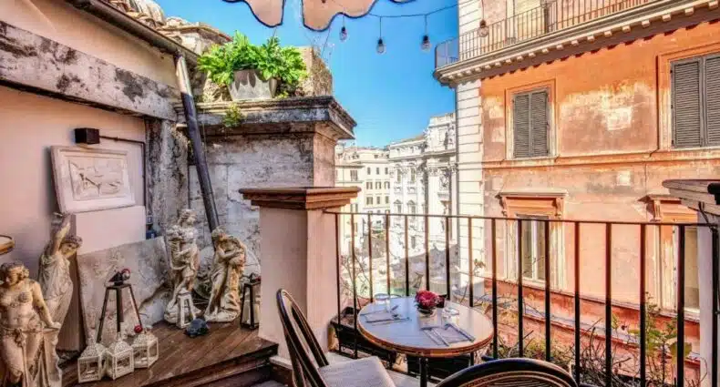 vista direta da praça no Relais Fontana Di Trevi Hotel, um dos hotéis perto da Fontana di Trevi em Roma, com mesinha e cadeiras, esculturas de um lado e vista total da fonte