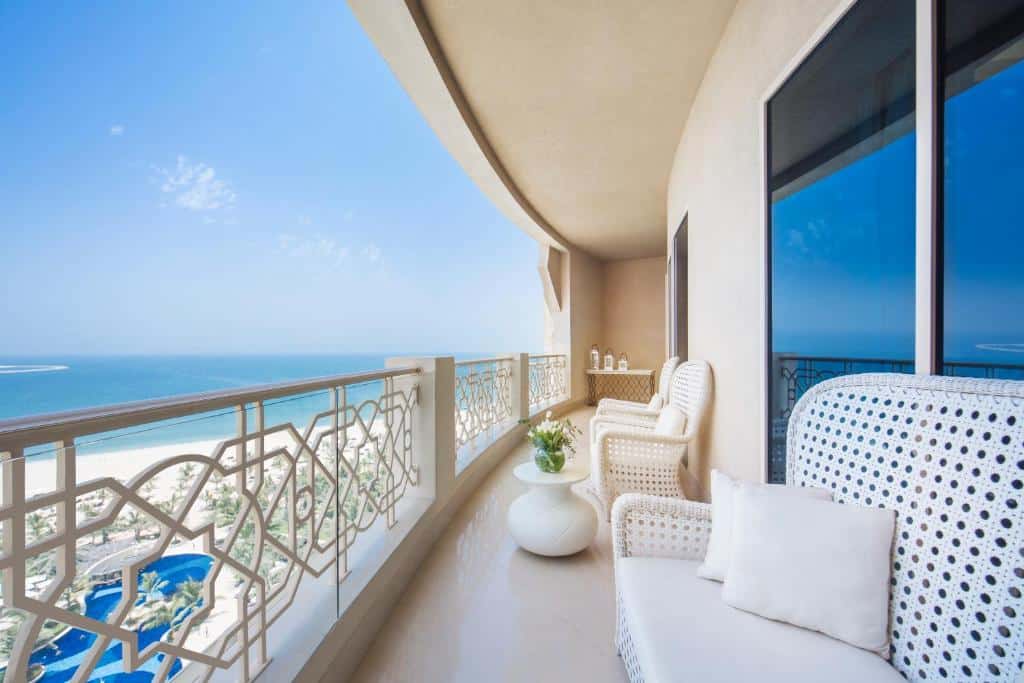 Varanda de um dos quartos do Waldorf Astoria Ras Al Khaimah com vista direta para a piscina da propriedade e o mar