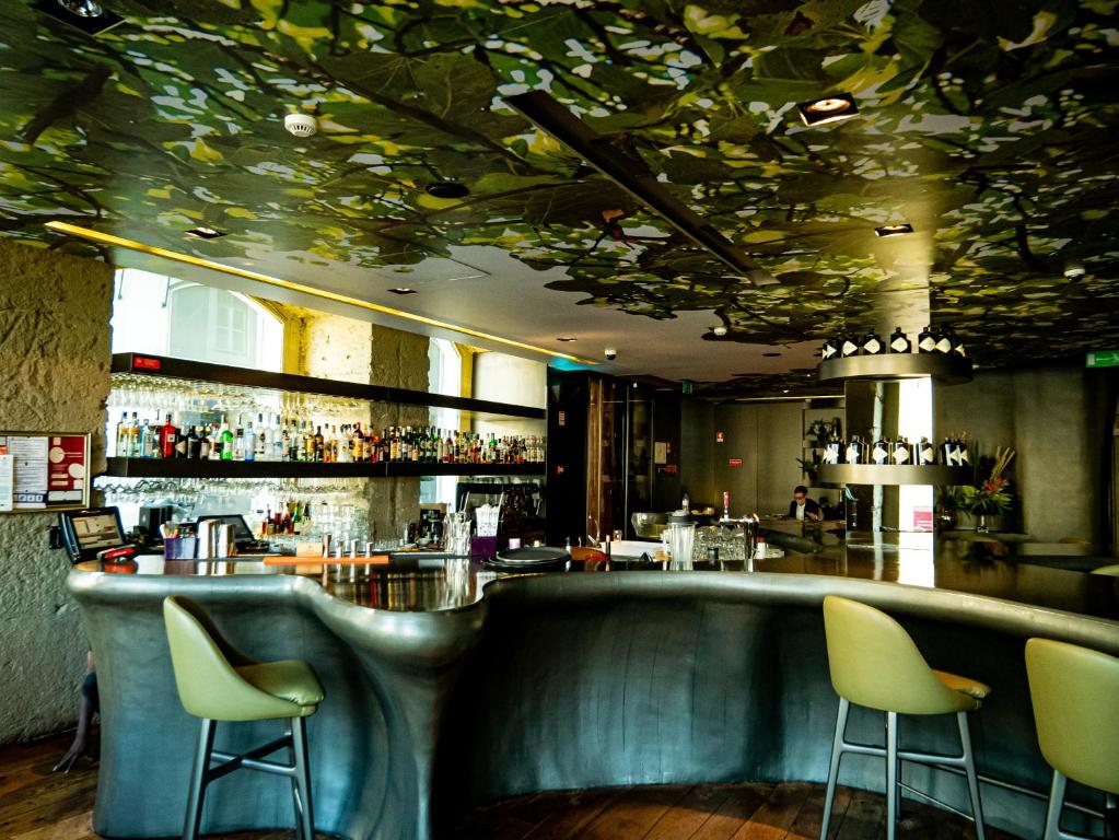 Bar do Figueira by The Beautique Hotels em estilo contemporâneo e em tons de verde musgo, o balcão tem um formato orgânico e o teto é inteiro pintado com flores
