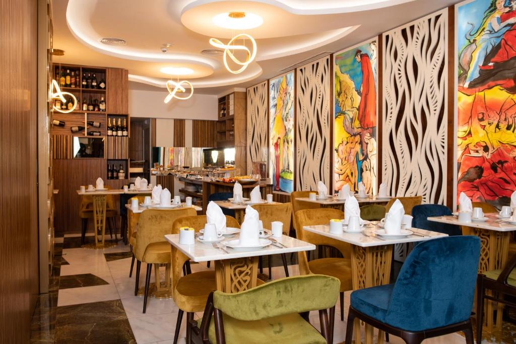 Área de refeições do Be Poet Baixa Hotel com uma parede decorada com pinturas coloridas, as mesas são de madeiras e as cadeiras estofadas em cores diferentes