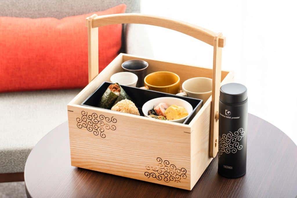 Imagem de uma lancheira de madeira com sushi e xícaras dentro no Karaksa Hotel Premier Tokyo Ginza.