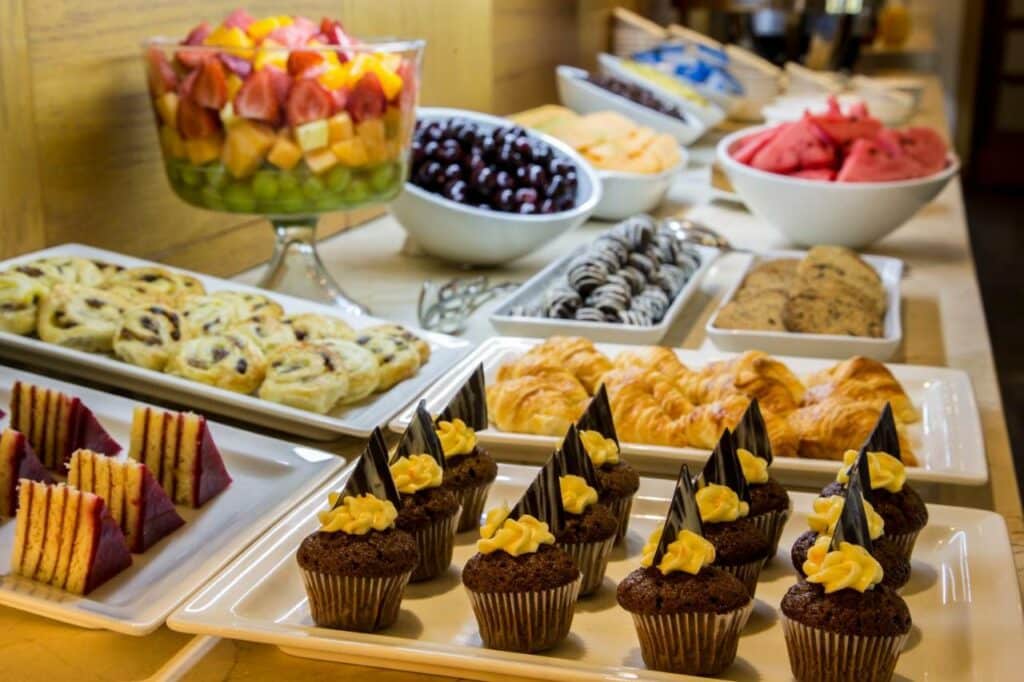 Café da manhã do hotel Best Western Marina del Rey. É possível ver vários tipos de frutas como morangos, melancias, uvas, jabuticabas etc,. Há também bolos, cupcakes e croissants.