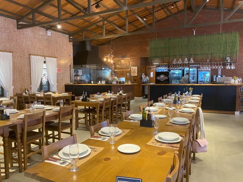 Espaço interno do restaurante BraZedo, com mesas postas para receber os clientes