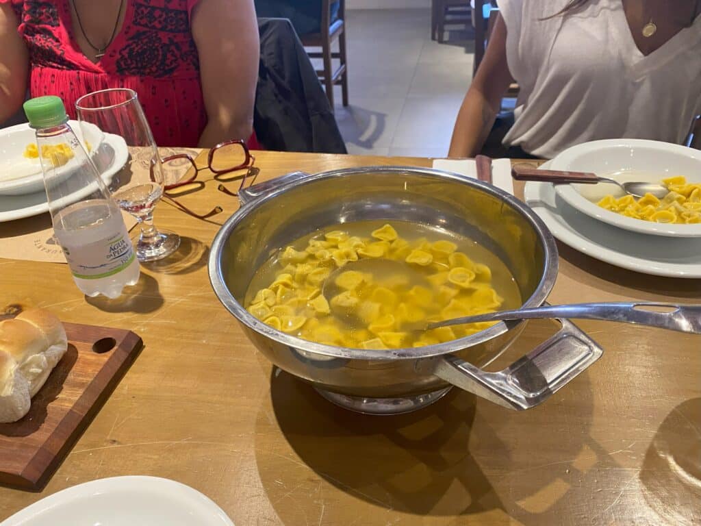 Prato de sopa de capeletti sobre mesa de madeira do restaurante BraZedo