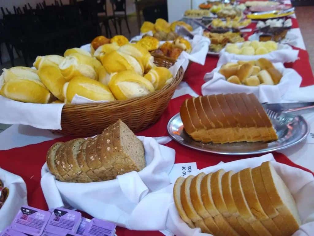 Imagem de um buffet de café da manhã na Pousada Casablanca. Podemos ver vários tipos de pães sobre a mesa.