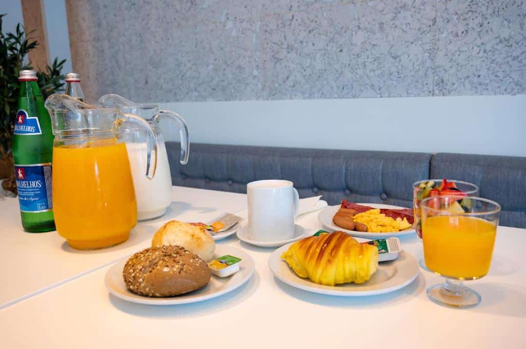 Mesa com café da manhã do Park Hotel Porto Aeroporto com sucos e pães.