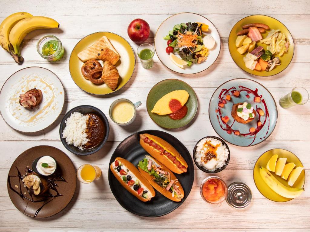 Imagem tirada de cima de uma mesa com vários pratos de comida no Tokyo Bay Shiomi Prince Hotel. Na foto podemos ver frutas, pães, arroz, sucos, carnes, etc.