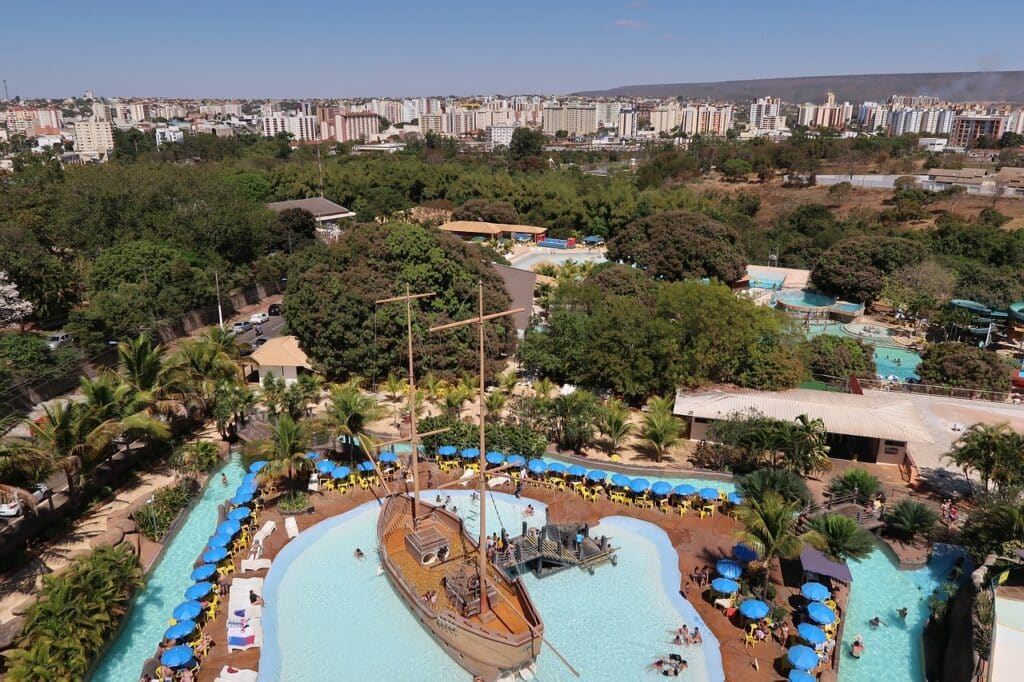 Imagem aérea da cidade de Caldas Novas em Goiás mostrando em baixo uma parte do parque aquático com um barco pirata, no meio da foto e em volta do parque aparece algumas árvores verdes e ao fundo os prédios, ilustrando post Hotéis em Caldas Novas.