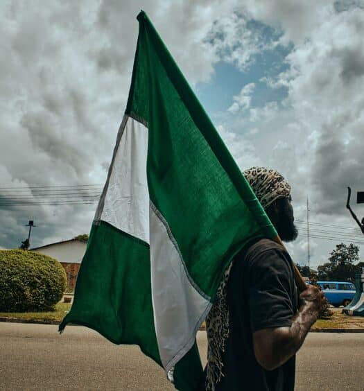 Homem segurando a bandeira na Nigéria durante o dia. Representa seguro viagem Nigéria.