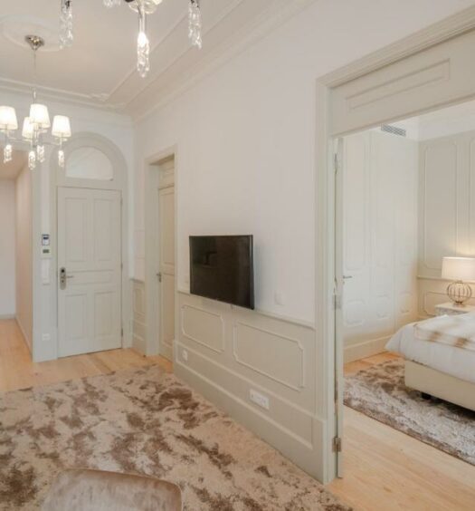 Sala de estar do Porto Deluxe Apartments, com sofá e TV a frente e ao fundo uma cama de casal do lado direito. Representa airbnb no Porto.