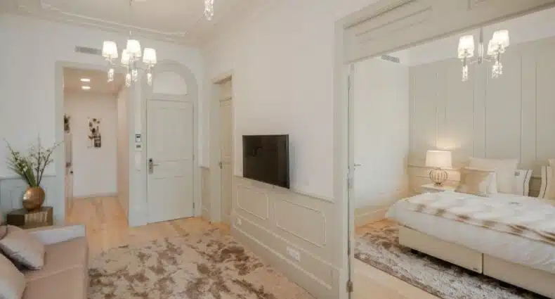 Sala de estar do Porto Deluxe Apartments, com sofá e TV a frente e ao fundo uma cama de casal do lado direito. Representa airbnb no Porto.